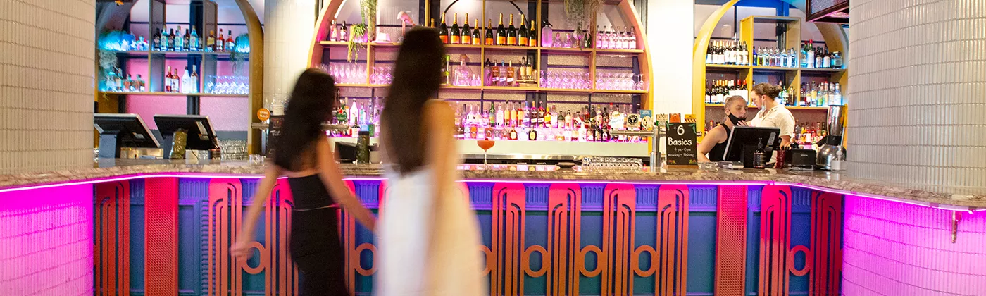 Two women walking in front of pink bar