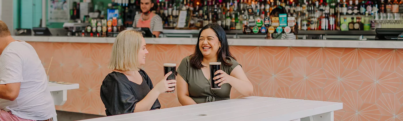 Two women (blonde and brunette) cheersing a beer at The Prince Consort