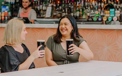 Two women (blonde and brunette) cheersing a beer at The Prince Consort