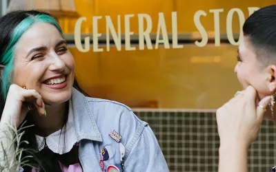 Two women sitting outside NUG General Store