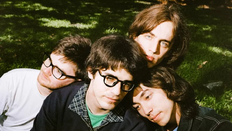 4 persons huddled with grass parkland in background