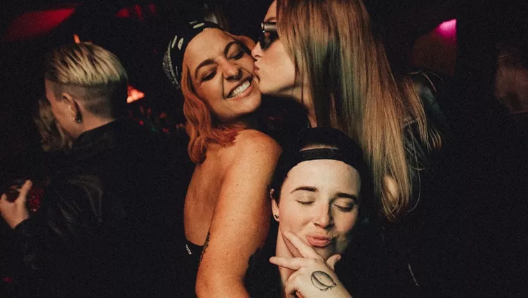 three persons with one pair kissing