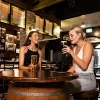 One brunette female and one blonde female sitting around a table at Finn McCools. With beers in hand. 