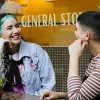 Two women sitting outside NUG General Store